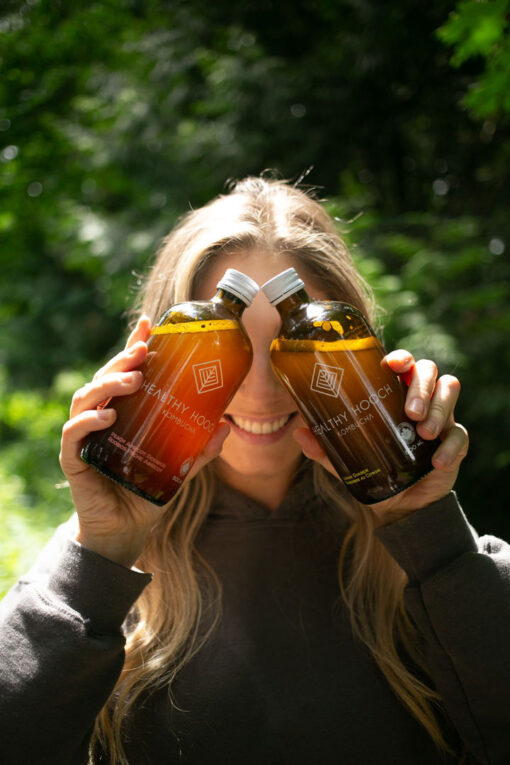 Girl holding two bottles of healthy hooch kombucha in front of her eyes