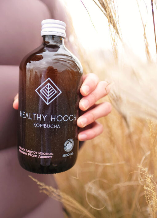 bottle of healthy hooch in a woman's hand with wheat in the background