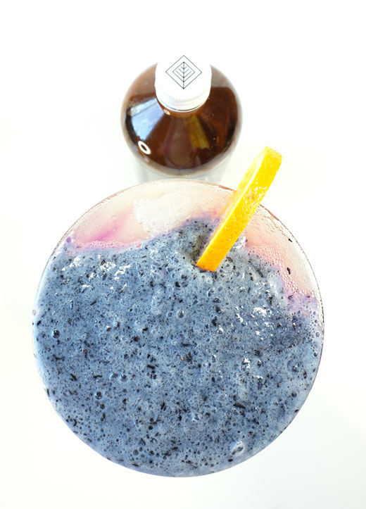 glass of ocean breeze cocktail next to a bottle of healthy hooch kombucha